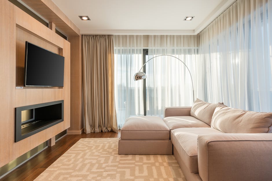 Bright and spacious living room featuring a modern design with a beige sofa, flat screen TV, and elegant curtains.